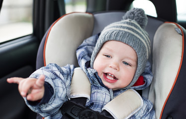 happy toddler  boy sitting in the car seat