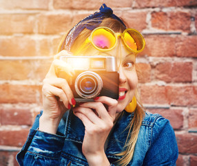 smiling girl with vintage camera taking photo with flash on bric