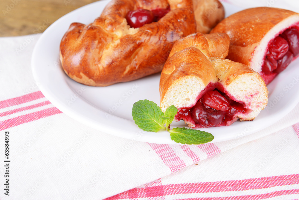 Fresh baked pasties with cherry on plate on table close-up