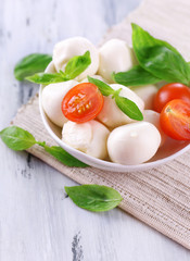 Wall Mural - Tasty mozzarella cheese with basil and tomatoes in bowl,