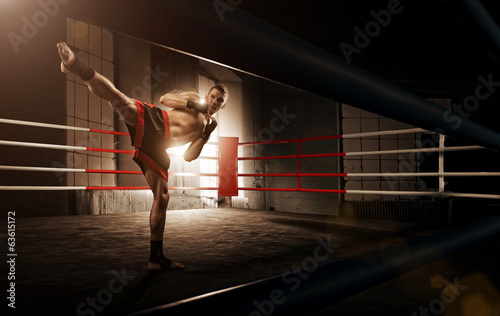 Cuadros en Lienzo Young man kickboxing in the Arena