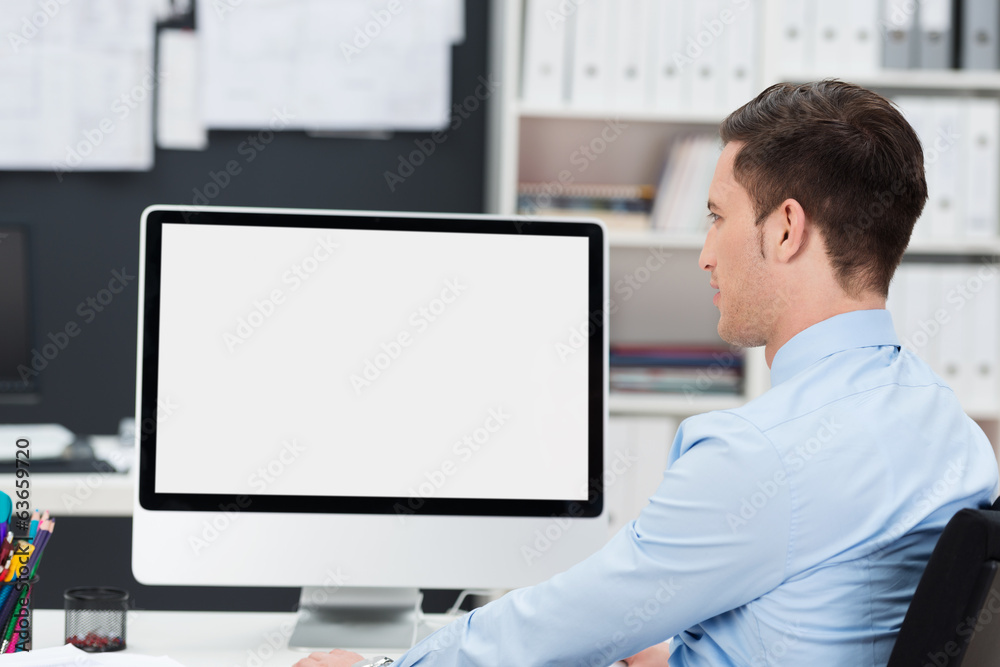 geschäftsmann im büro schaut auf pc-monitor