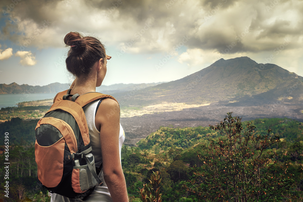 Lady tourist with a backpack standing on top of the mountain - obrazy, fototapety, plakaty 