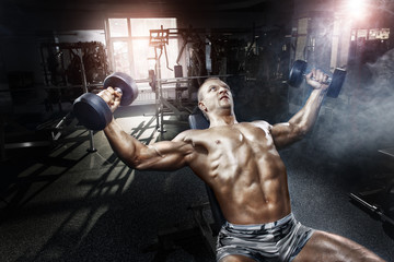 Wall Mural - Athlete in the gym training with dumbbells