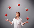 young girl standing and juggling with red balls