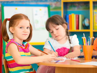 Fototapete - Two cute little girls drawing at school