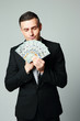 © Drobot Dean - Businessman holding group of dollar bills on a gray background