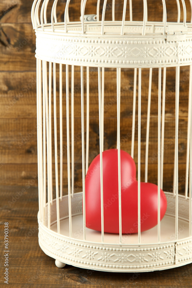 Heart in decorative cage  on wooden background