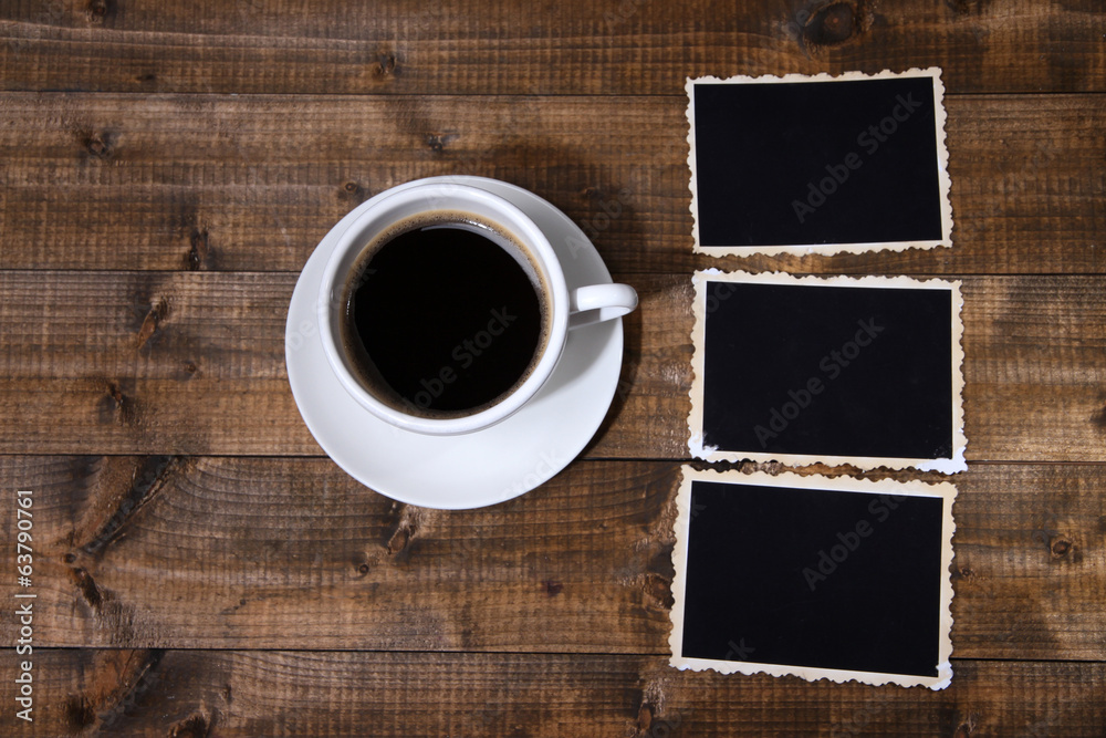 Coffee cup and old blank photos, on wooden background
