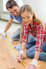 smiling couple measuring wood flooring