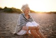 © Jacob Lund - Cheerful old woman sitting on the beach