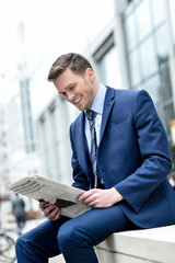 Wall Mural - Smiling businessman reading paper at outdoors