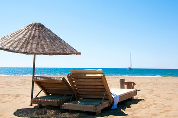 Sunbeds and rattan parasols on sandy seaside.