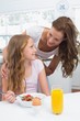 © lightwavemedia - Mother looking at daughter while having breakfast in kitchen