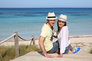 Wall Mural - Couple on vacation sitting by the beach