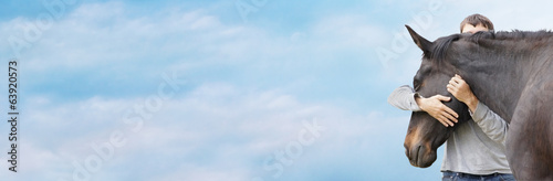 Fotografía Man hugging his black horse's head against sky, banner