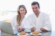 © lightwavemedia - Couple using laptop on breakfast table