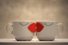 Two Coffee Cups With Red Hearts As A Kissing Lips