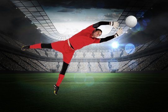 Composite image of fit goal keeper jumping up