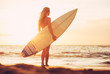 Surfer girl on the beach at sunset