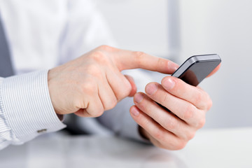 Wall Mural - male hand holding a cell phone and writing sms
