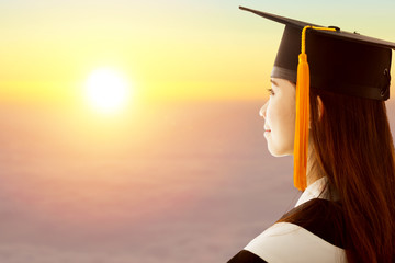 female graduation is thinking future with sunset background
