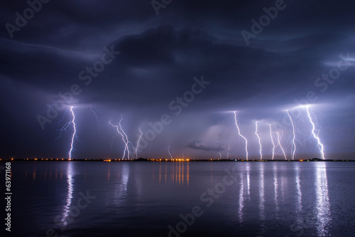 Fotografie, Obraz Thunderstorm and lightnings in night over a lake with reflaction