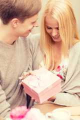 Wall Mural - romantic happy couple with gift in the cafe