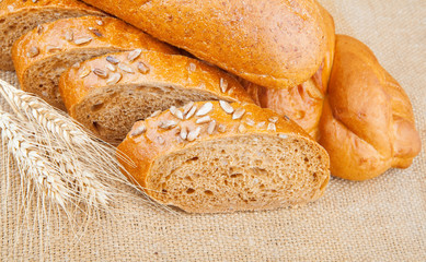 Assortment of baked breads with spikelets of wheat on burlap