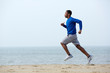 © mimagephotos - Young athletic man running at the beach