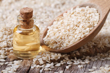 Fresh Sesame Oil In A Glass Bottle And Seeds In A Wooden Spoon