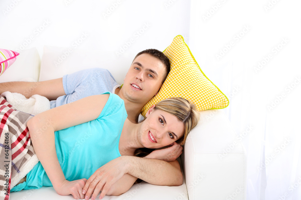Loving couple sitting on sofa, on home interior background