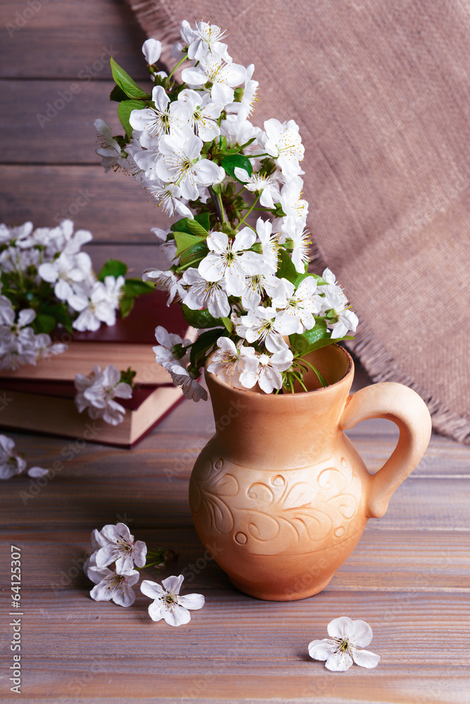 Beautiful fruit blossom in pitcher on table on grey background