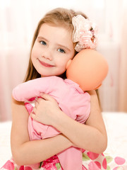 Poster - Adorable smiling little girl playing with a doll