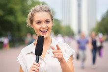 A Smiling Girl Reporter With Microphone In Hand