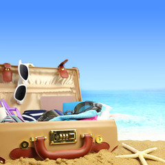 Full open suitcase on tropical beach background