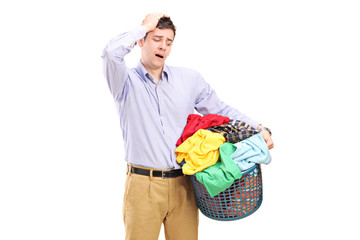 Wall Mural - Unhappy man looking at a basket full of laundry