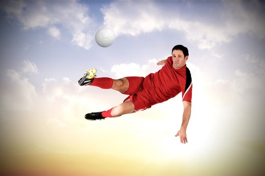 Composite image of football player in red kicking