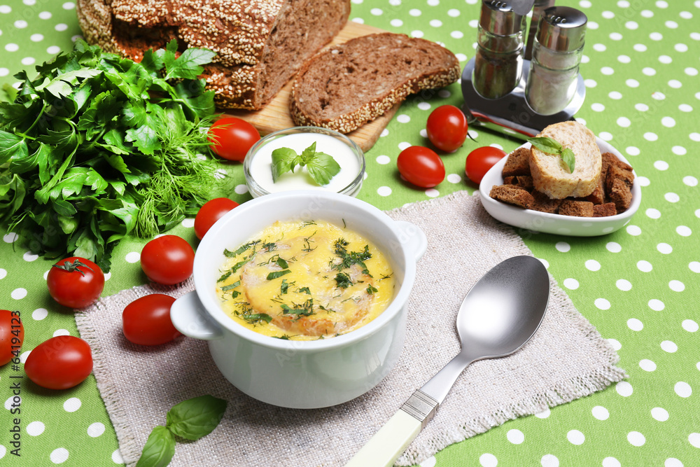 Tasty soup in saucepan on tablecloth, close up