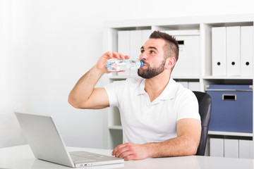 Handsome young man drinks water from a bottle