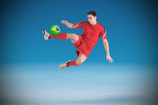 Composite image of fit football player jumping and kicking