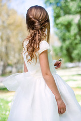 Girl in communion dress showing hairstyle.