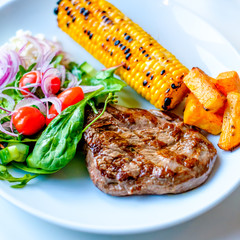 Grilled Beef Steak with some sallad on the side and corn