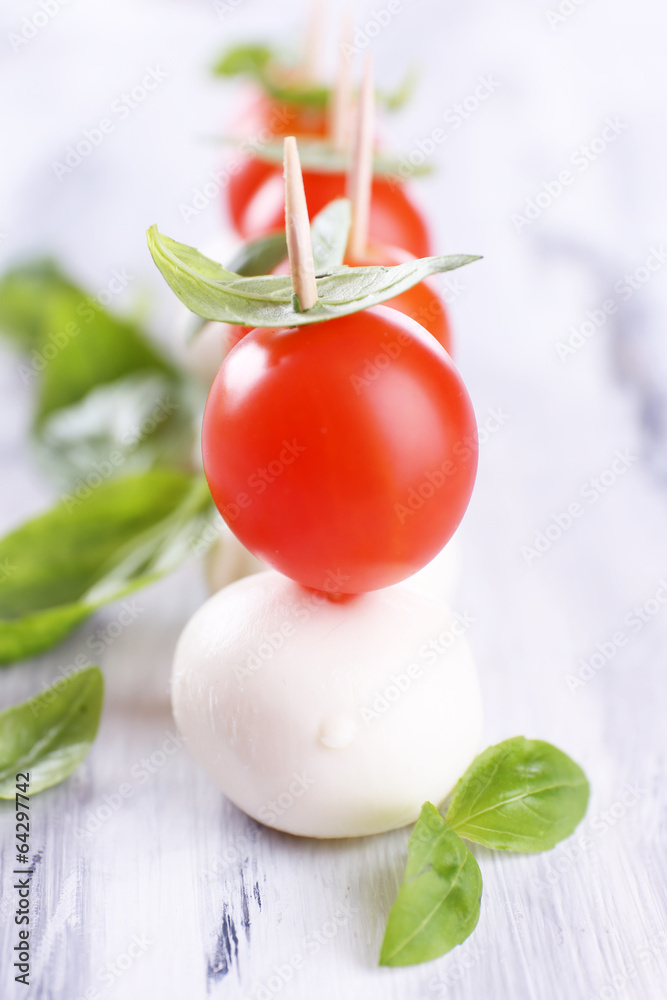 Tasty mozzarella cheese with basil and tomatoes, on wooden