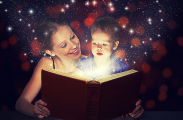 Wall Mural - mother and child baby daughter reading magic book in dark