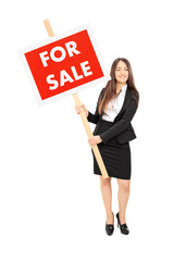 Canvas Print - Female real estate agent holding a for sale sign