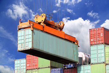 Wall Mural - Sea container lifted by a harbor crane with blue sky