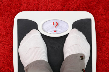 Female feet on bathroom scale with question mark symbol