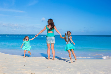 Wall Mural - Happy mother and her adorable girls having fun at tropical beach