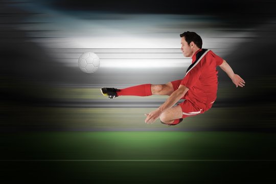 Composite image of football player in red kicking
